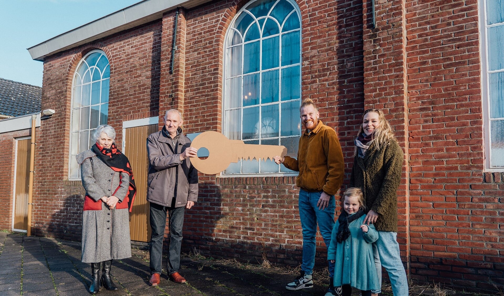 De symbolische sleutel van de Chr. Gereformeerde kerk wordt overhandigd door familie van Bergeijk (links) aan familie de Vries (rechts).