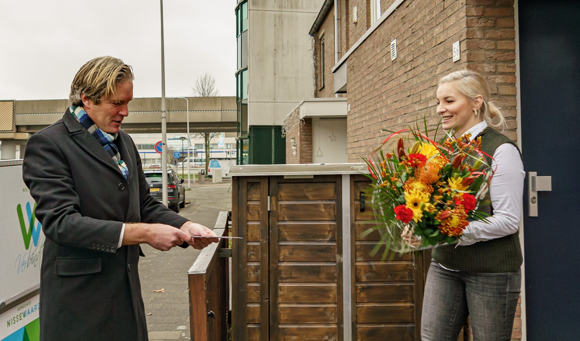 Als een volleerd bezorger levert de burgemeester een bloemetje af. 