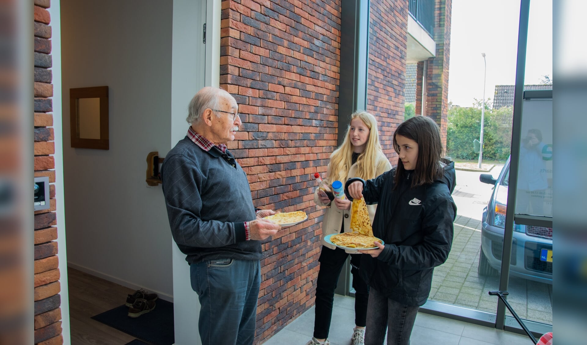Twee leerlingen verrassen een bewoner van Stadhuus met heerlijke verse pannenkoeken!  Foto: Sam Fish