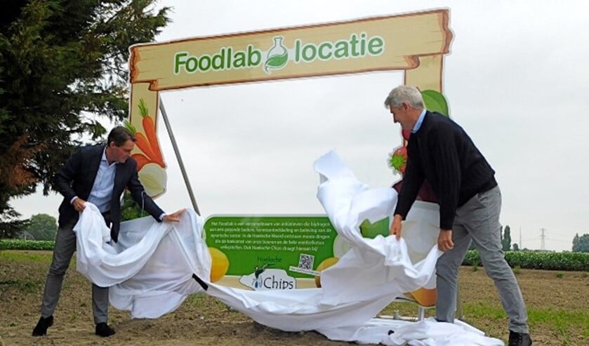 <p>Wethouder Paul Boogaard en Henk Scheele(rechts) onthullen het bord wat de Foodlab locatie aangeeft. (foto: Arie Pieters)</p>