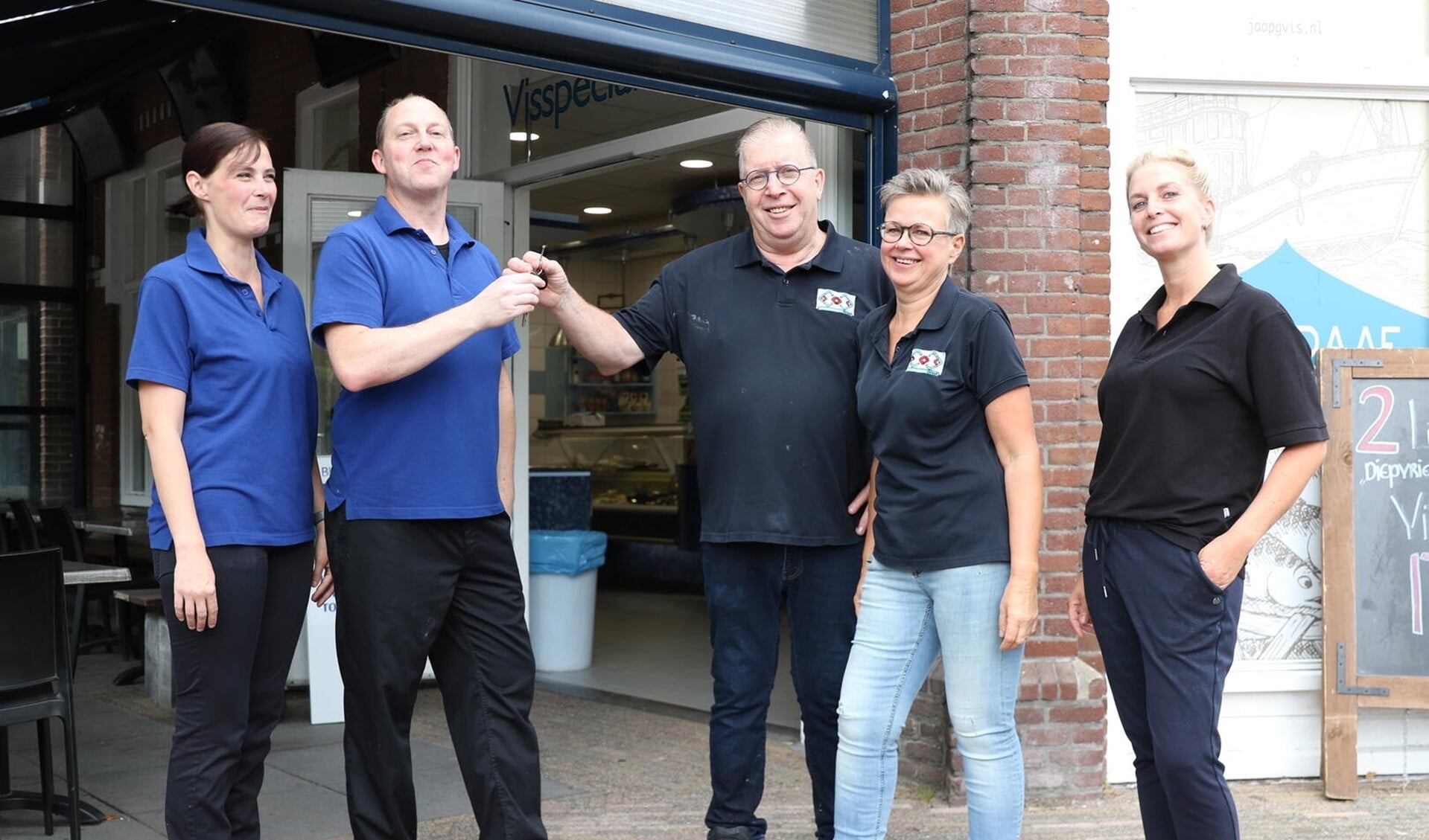 Jaap Graaf overhandigt de sleutel van zijn visspeciaalzaak aan de nieuwe eigenaar Cor van der Veer. Links Cors partner Nicole van der Heiden, rechts van Jaap zijn vrouw Connie en dochter Stacey.