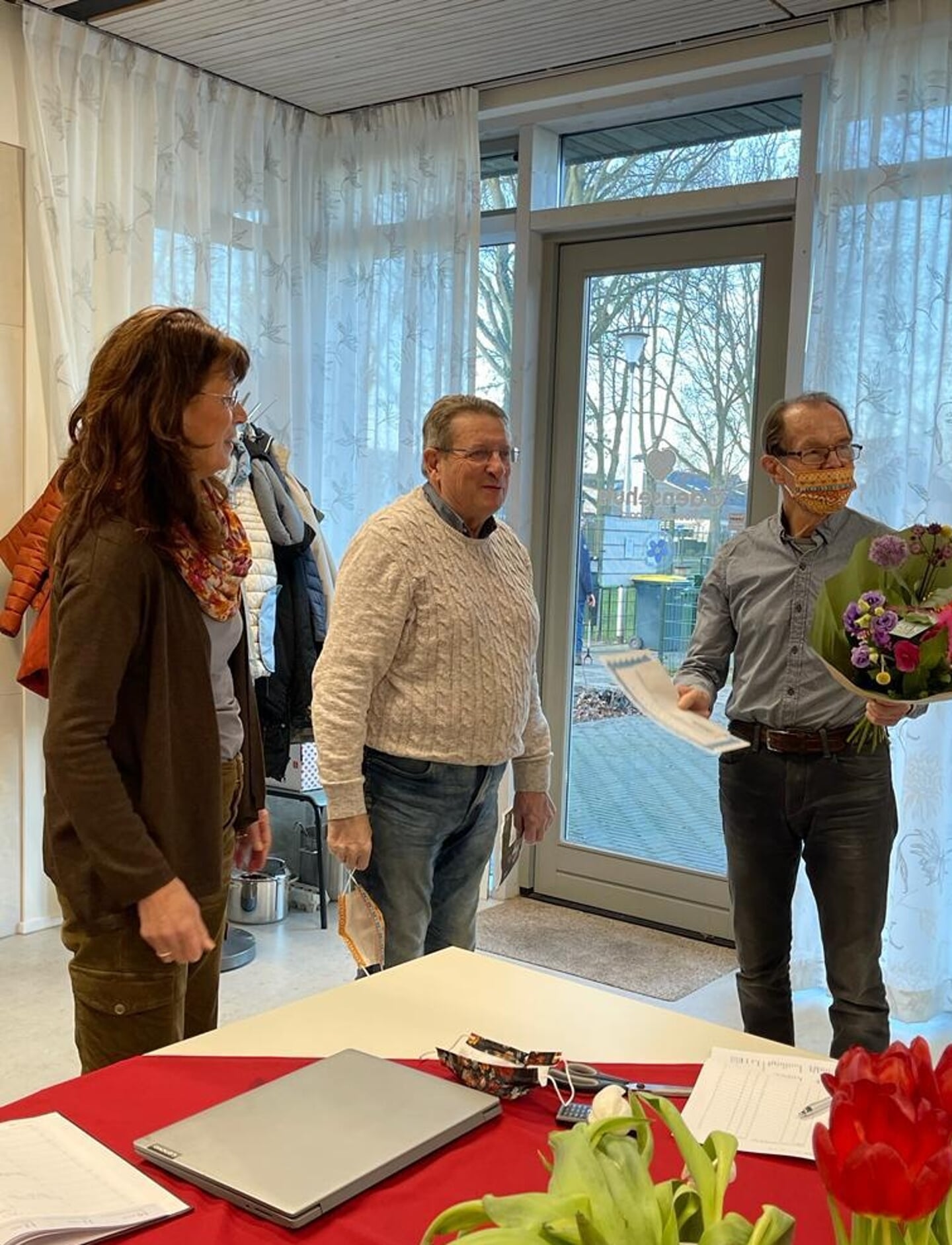 Ruud Solleveld (rechts) heeft een tegoedbon gekregen uit handen van zijn collega-vrijwilliger bij het Odensehuis Piet de Groot. Links Deborah van Abkoude, coördinator van het Odensehuis Hoeksche Waard. (foto pr Odensehuis)