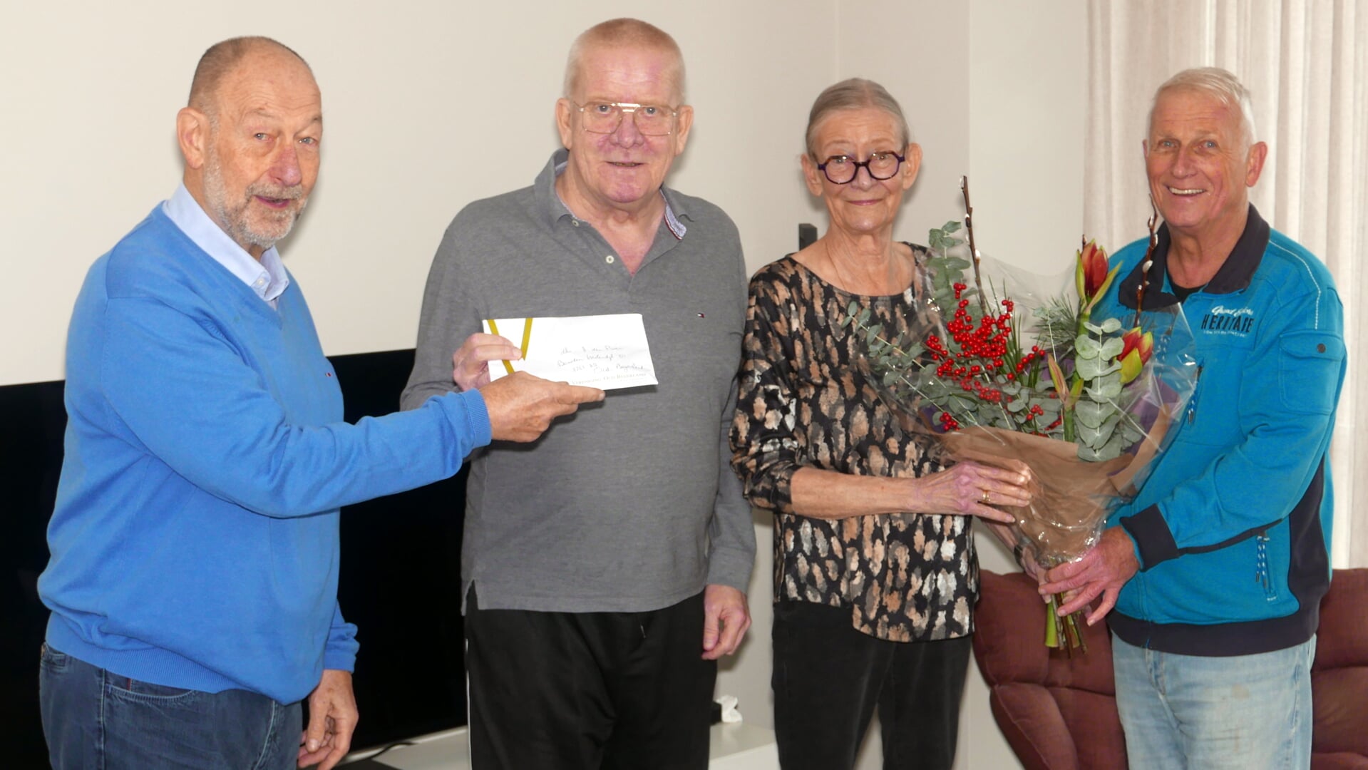 Pieter Jan in 't Veld (links) en Adri de Groot (rechts) bieden de heer en mevrouw Den Boer bloemen aan, mijnheer is het 500e lid van de Historische Vereniging Oud-Beijerland geworden. (foto: Jan Markx)
