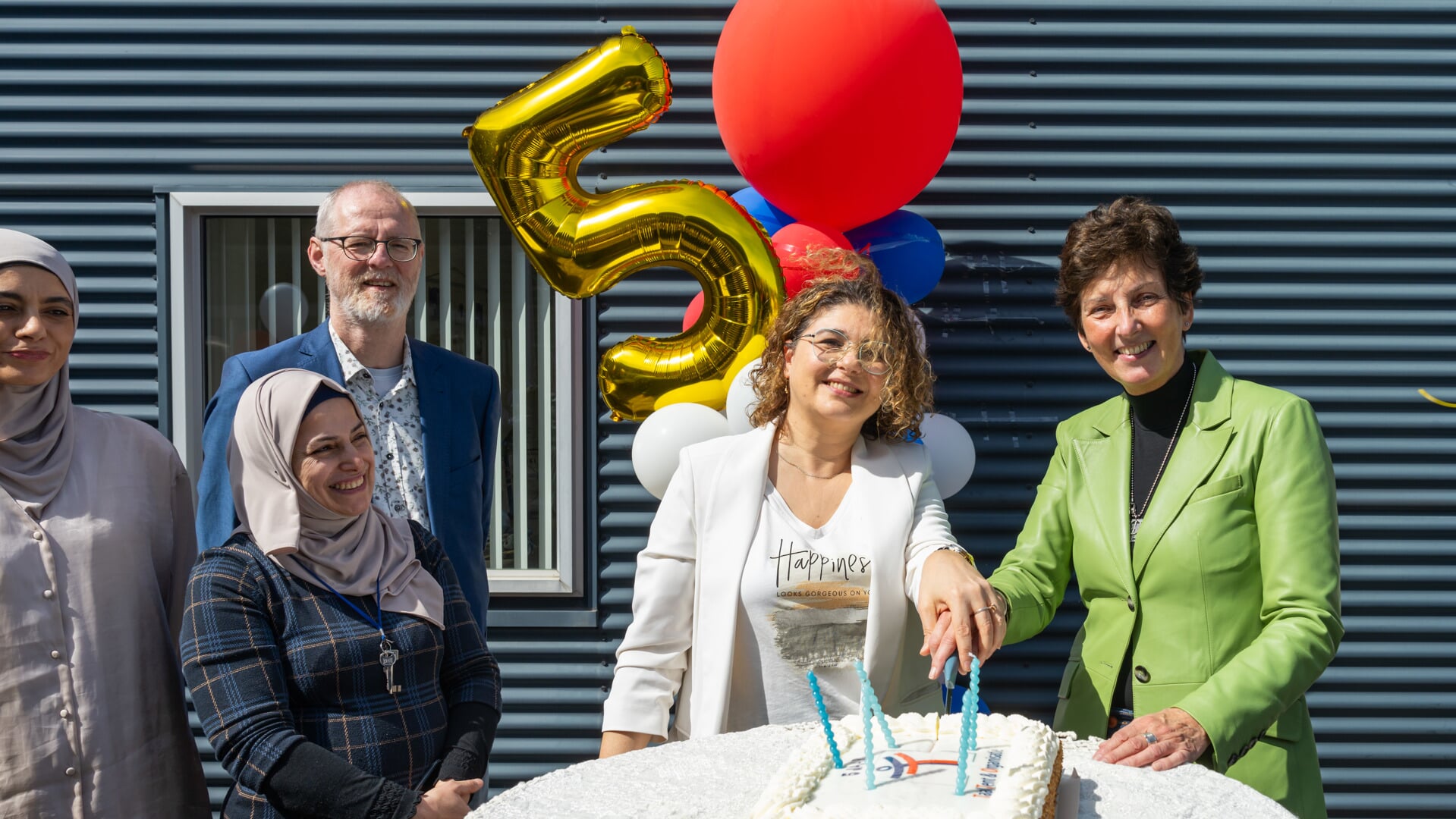 Wethouder Hanneke Stengs snijdt de taart aan ter ere van het eerste lustrum van Taaltent & Organisatie 