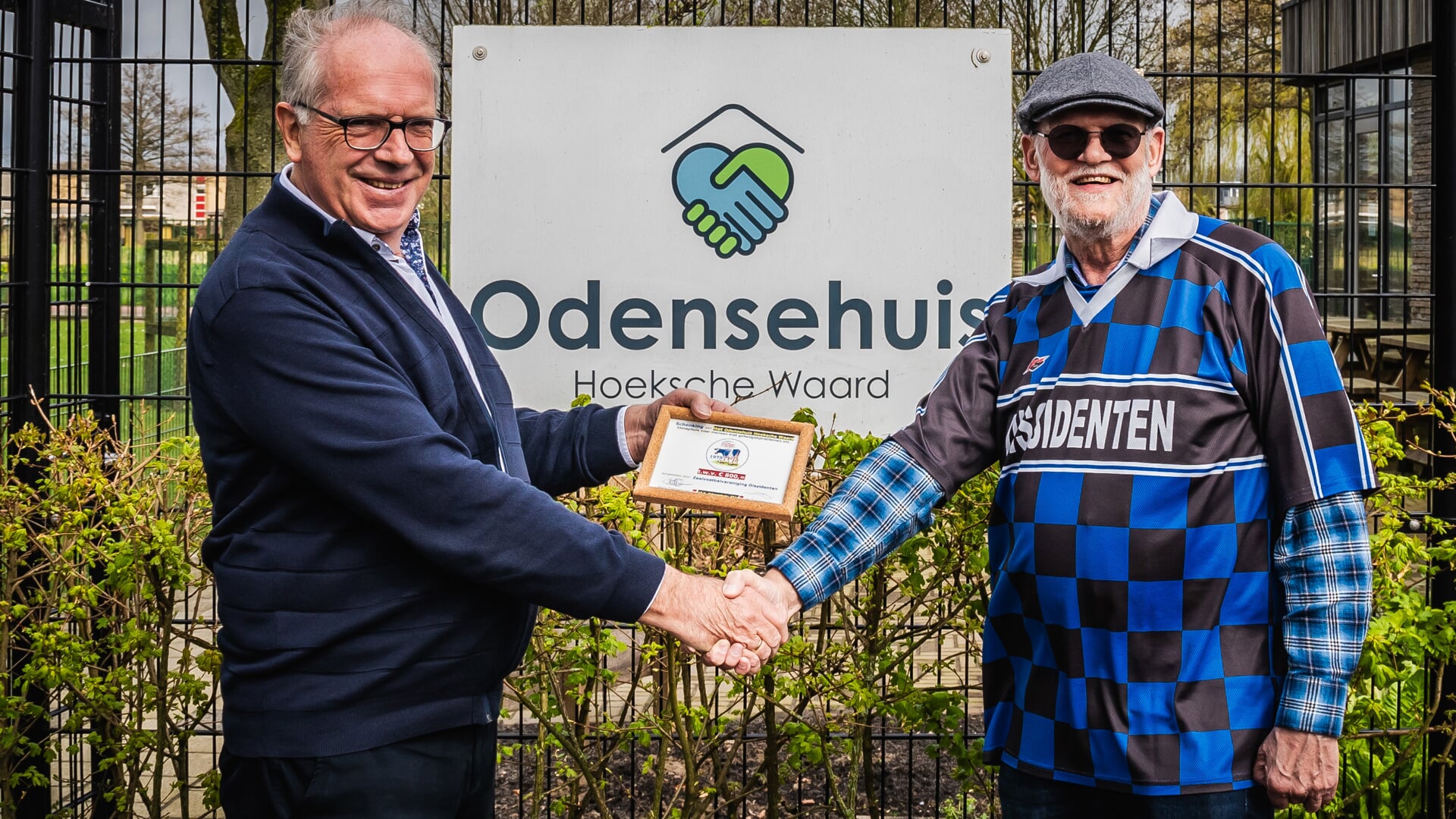 Jan Tolenaars (rechts) reikt het geld uit aan voorzitter Henk van Etten van het Odensehuis Hoeksche Waard. (foto Jaco de Vroet)