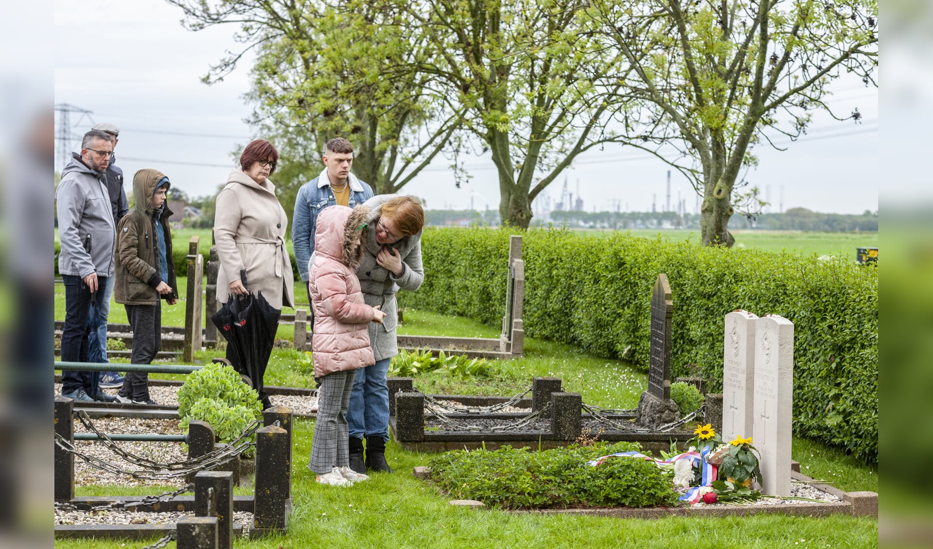 Aanwezigen leggen rozen op het graf van twee omgekomen piloten. 