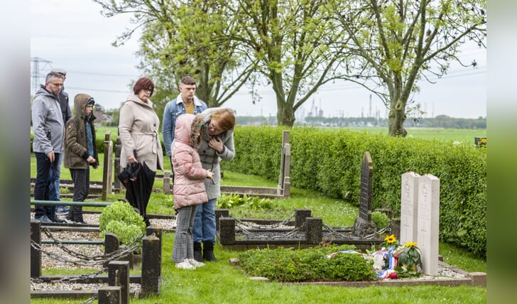 Aanwezigen leggen rozen op het graf van twee omgekomen piloten. 