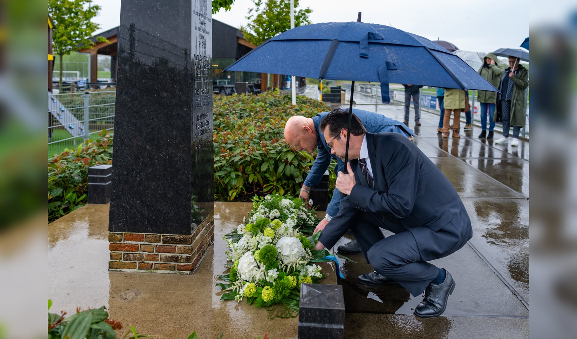Wethouder Hottentot legt samen met voorzitter Ad van der Bom een bloemstuk bij het monument van GHVV'13