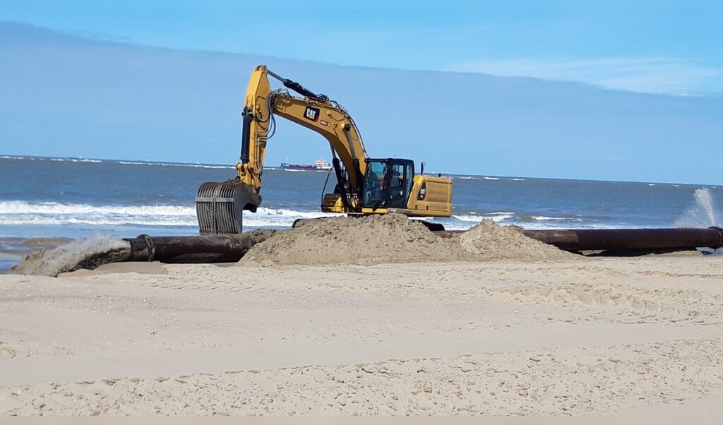 De sleephopperzuiger spuit het zand door de persleiding op het strand. De graafmachine zorgt voor de gelijkmatige verdeling.