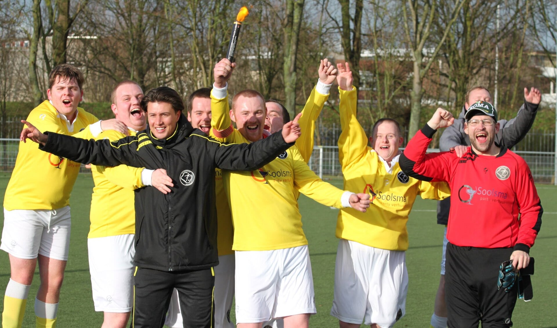 Trainer Jens de Ridder viert de overwinning samen met de spelers.
