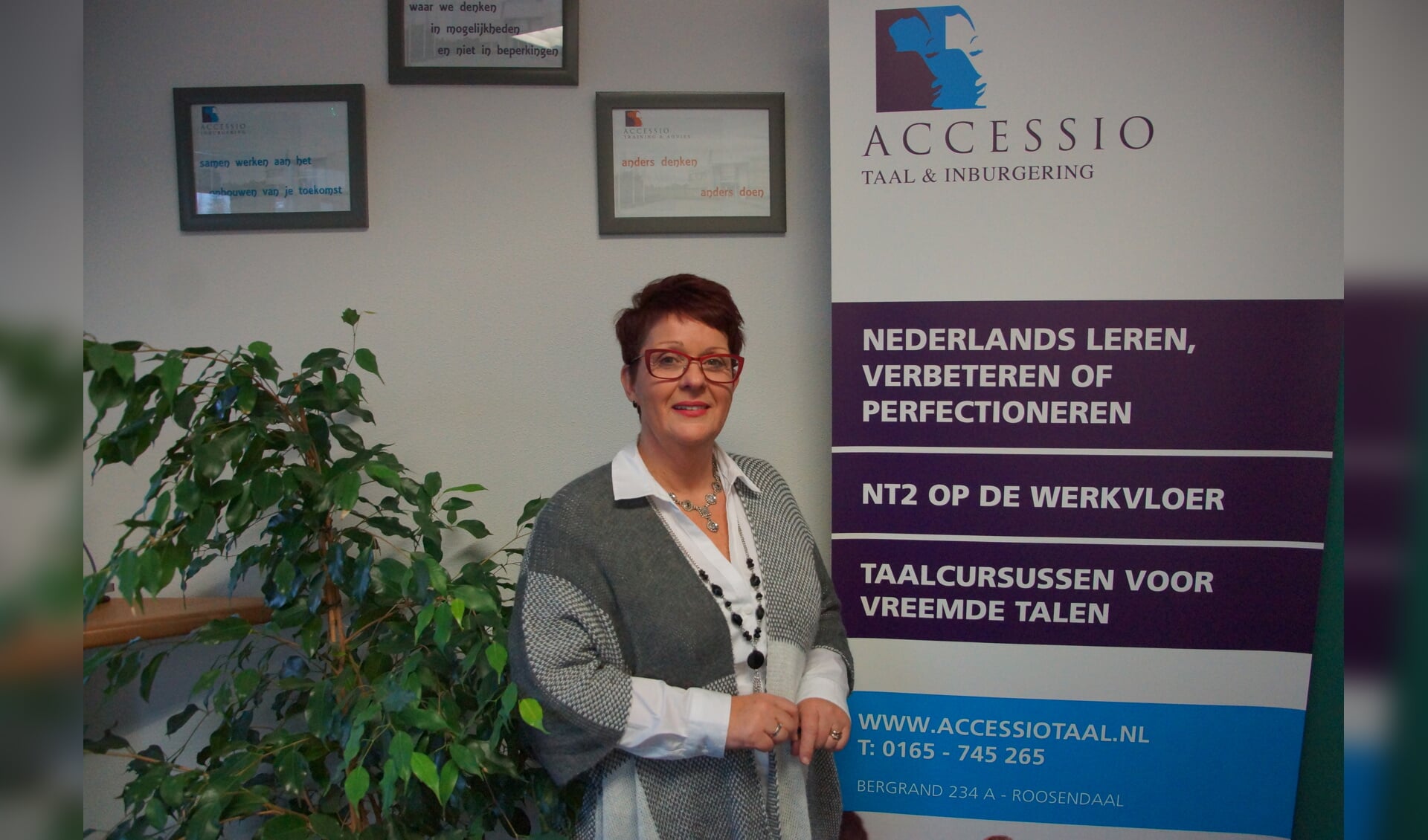 Mevrouw Marie-Jos Baselier, manager van Accessio Taal & Inburgering, bij een van de banners van het bedrijf. FOTO RENÉ BRUIJNINCX