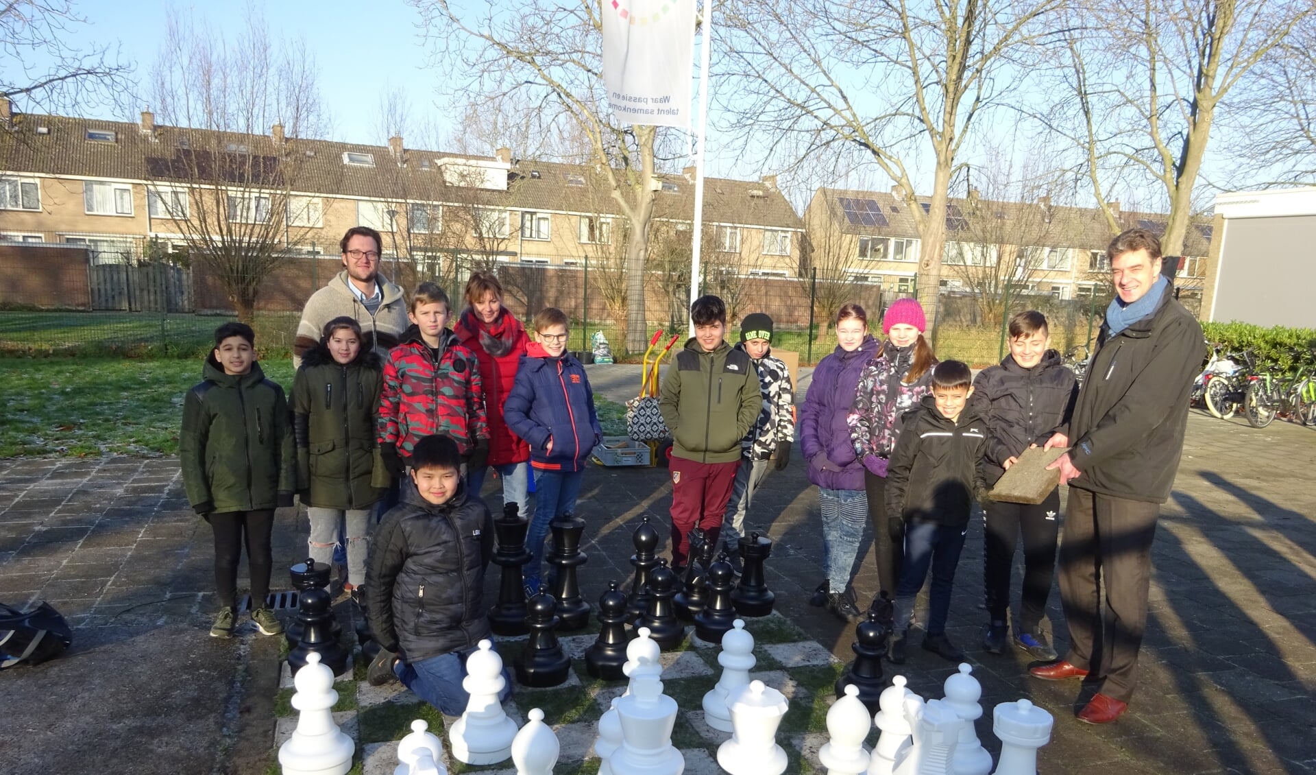 Groep 8 van Het Element overhandigt een stoeptegel aan wethouder Chris Dekker. FOTO MARIELJA TEN BRUGGENCATE