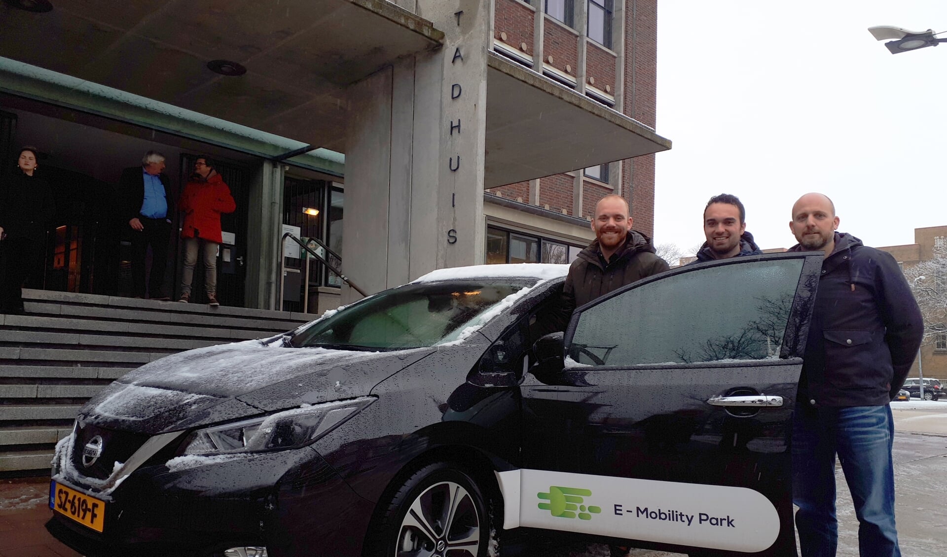Wethouder Sem Stroosnijder en David Tolhoek en Sjoerd de Jong (vlnr) van de stichting bij de elektrische deelauto.