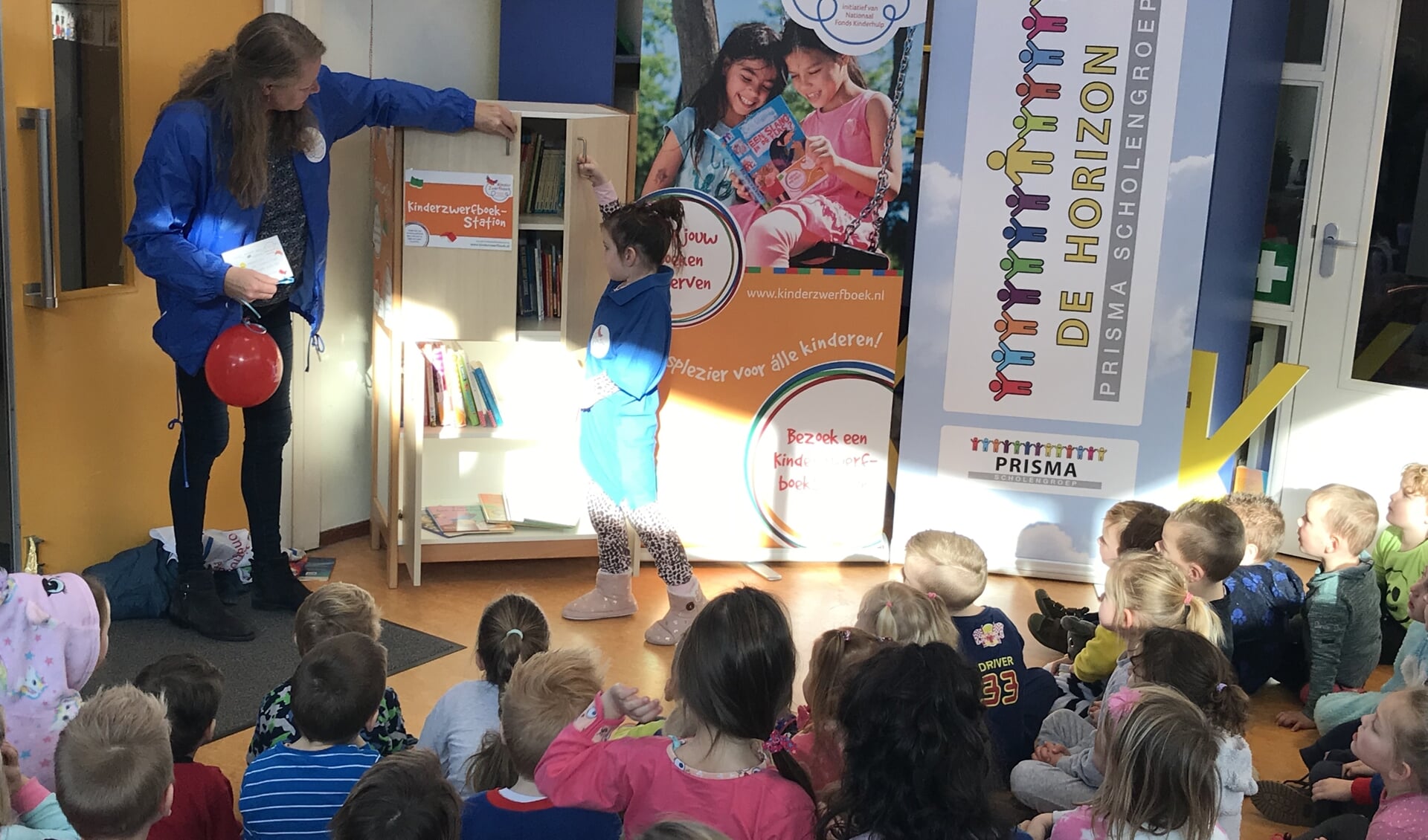 De jarige Ruhmen mag helpen met de opening van het kinderzwerfboekenstation.