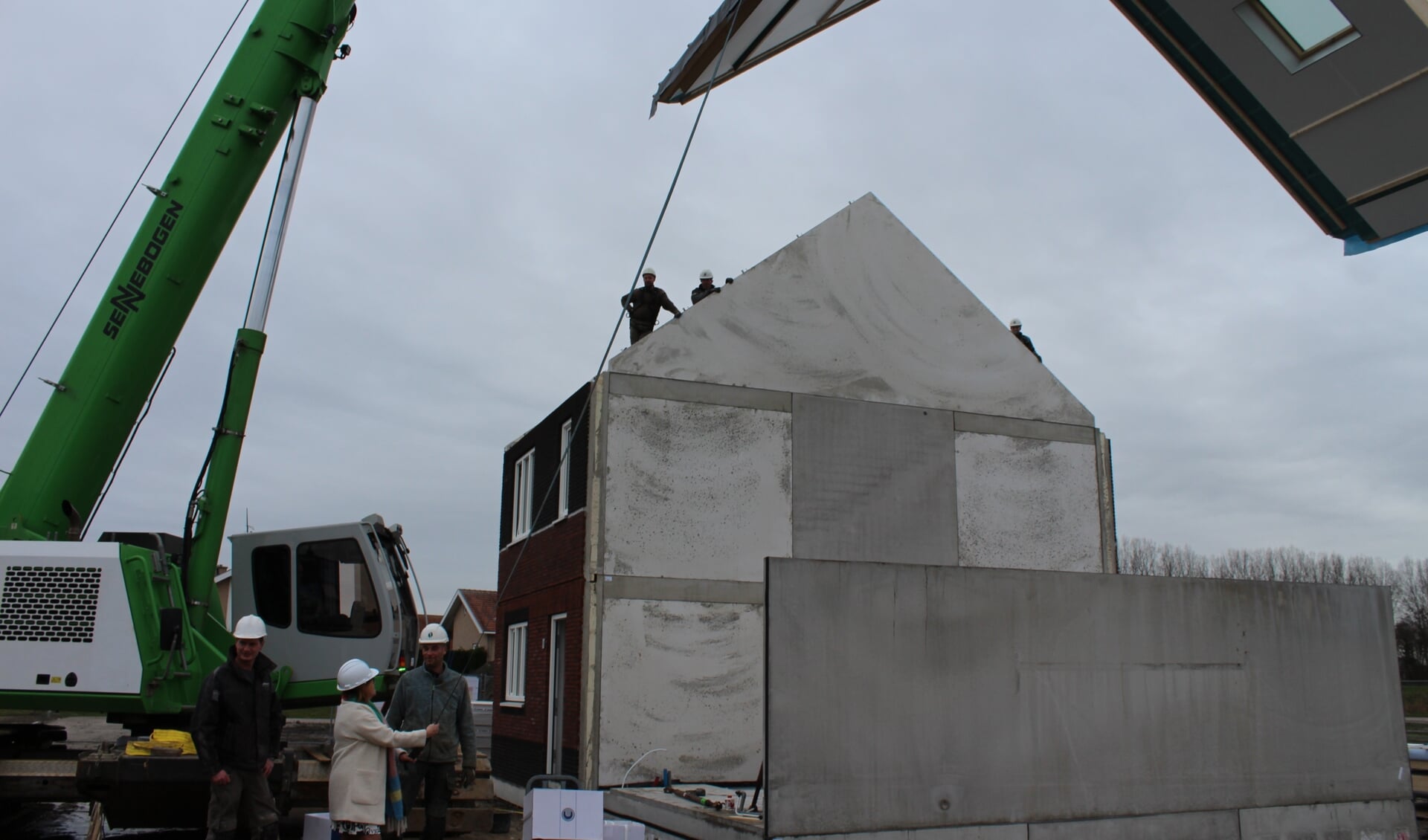 Wethouder Baartmans helpt bij het plaatsen van een dakelement op de 0 op de meter woningen aan de Lunet in Steenbergen