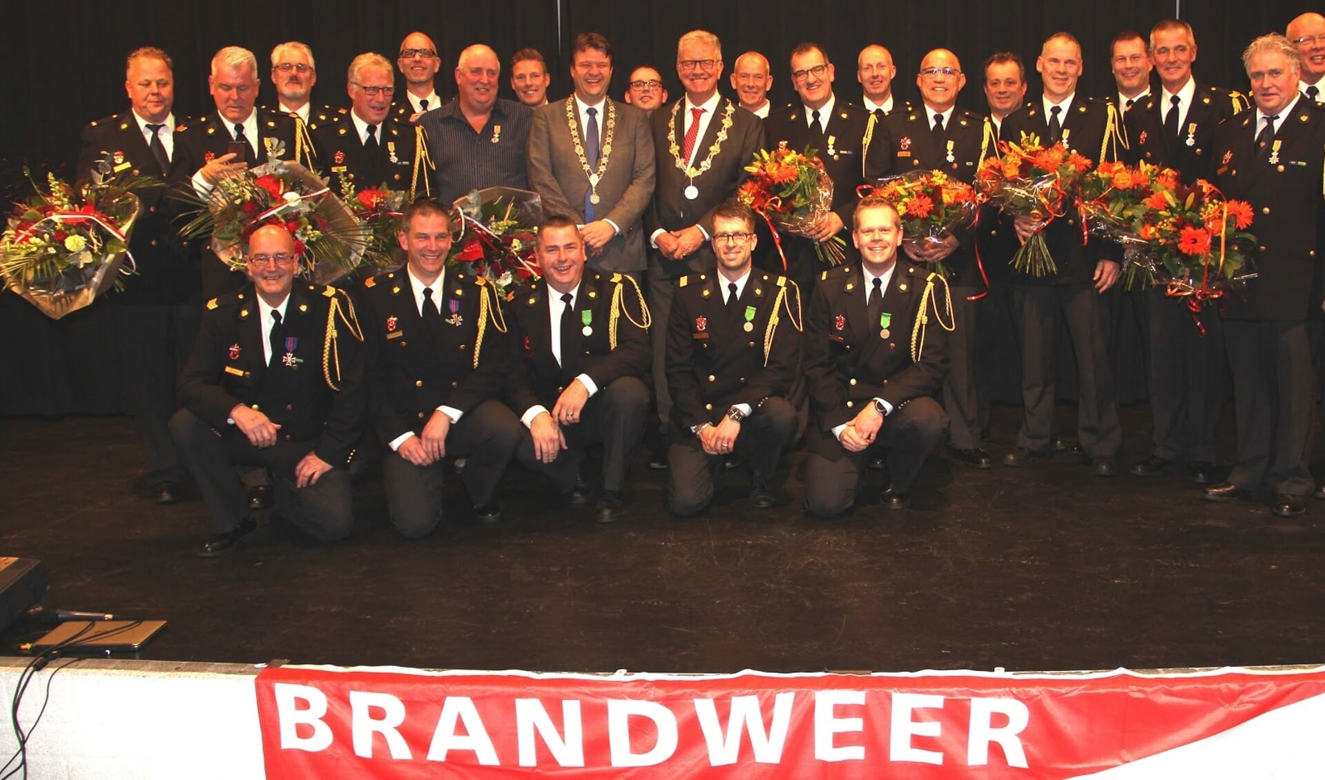 Alle gedecoreerde brandweermannen en -jubilarissen in gezelschap van burgemeesters Van Midden en Petter.