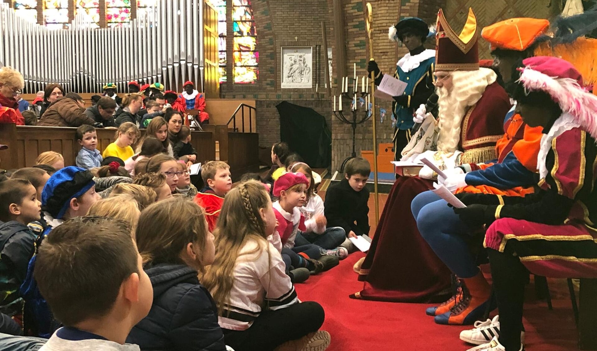 Kinderen zouden het liefst allemaal op schoot kruipen, als Sinterklaas vertelt tijdens de gezinsviering in de Lourdeskerk.