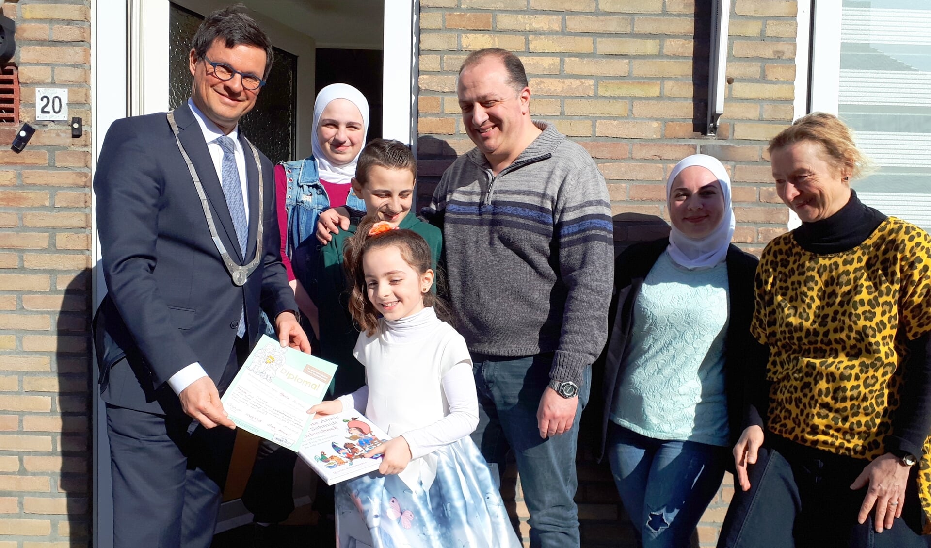 Massa toont met haar familie en de burgemeester trots haar diploma en het boek dat ze van Ivonne (r) kreeg. 