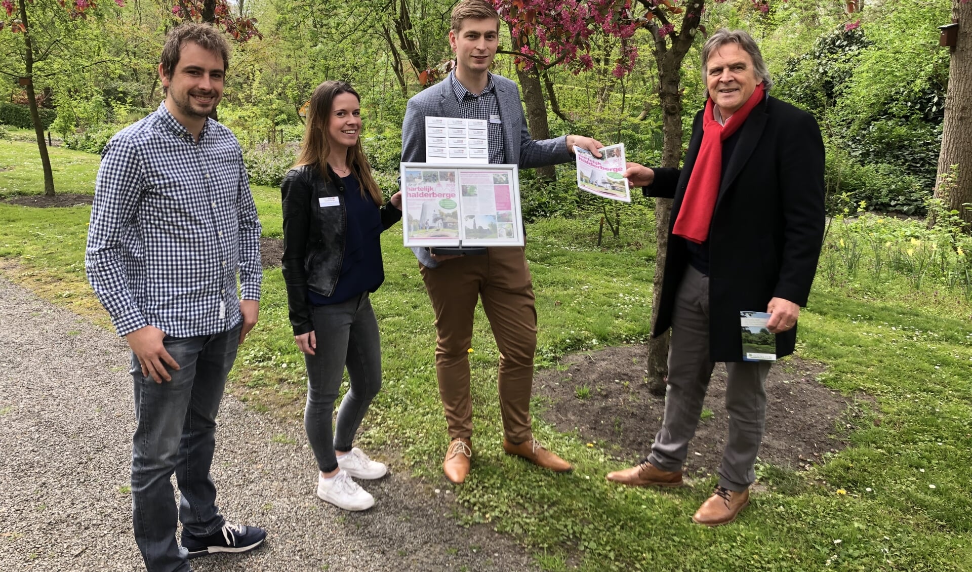 De krant wordt overhandigd door (vlnr) Jort Schoemaker, Simone Konings en Wim Hofstede aan Johan van Oosterhout  van het Arboretum. 