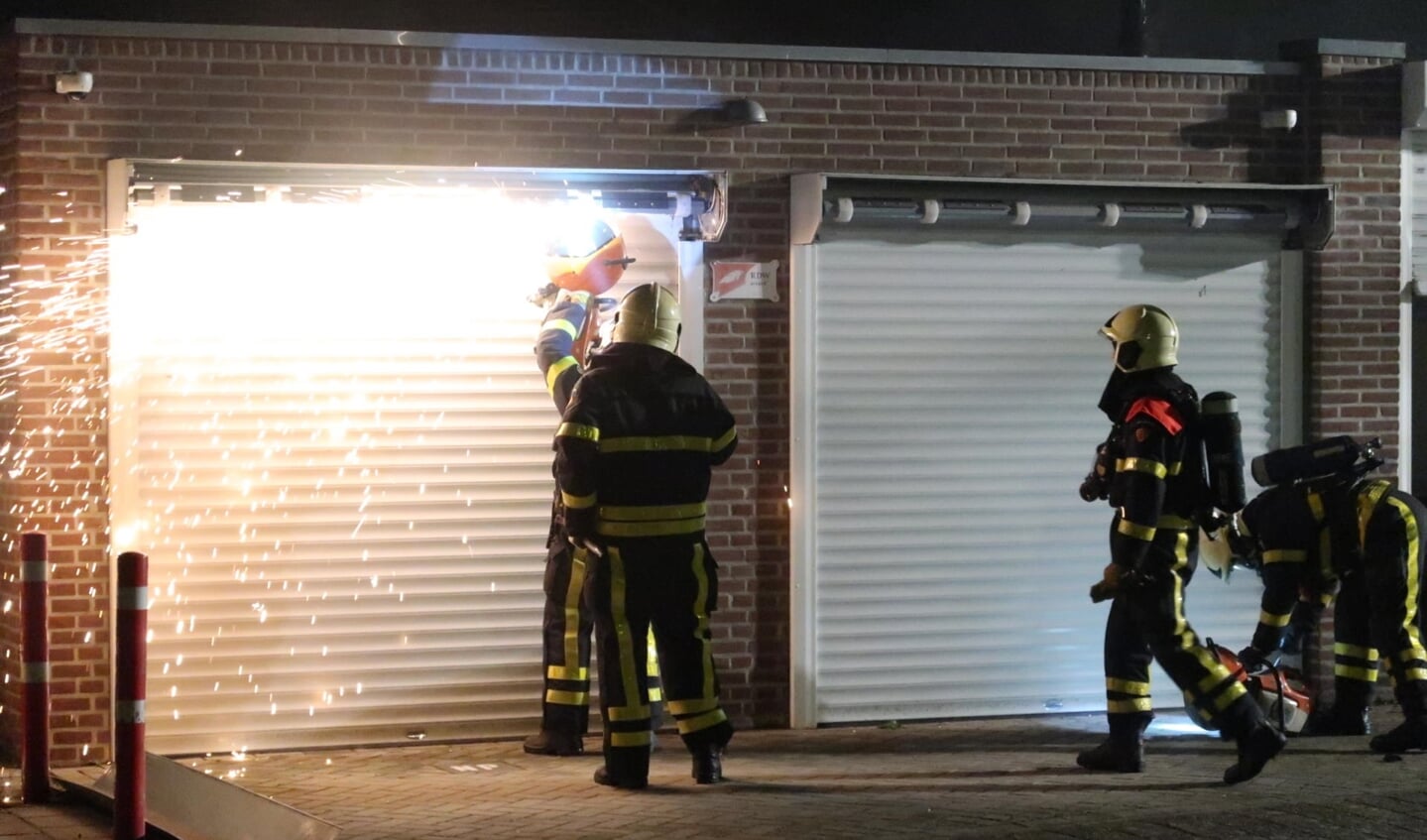 De brandweer breekt de garage open.
