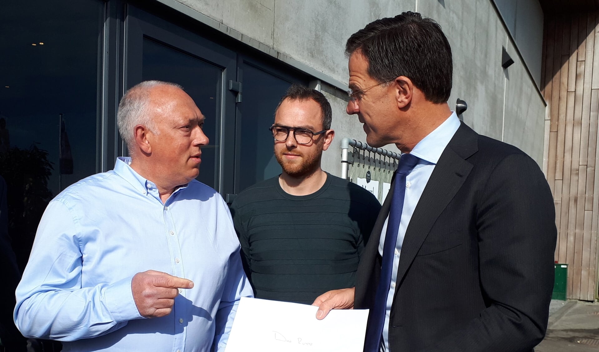 Premier Mark Rutte (r) krijgt bij Proef Zeeland op Neeltje Jans een brief aangeboden van pulsvissers Cas en Dave Caljouw uit Arnemuiden.