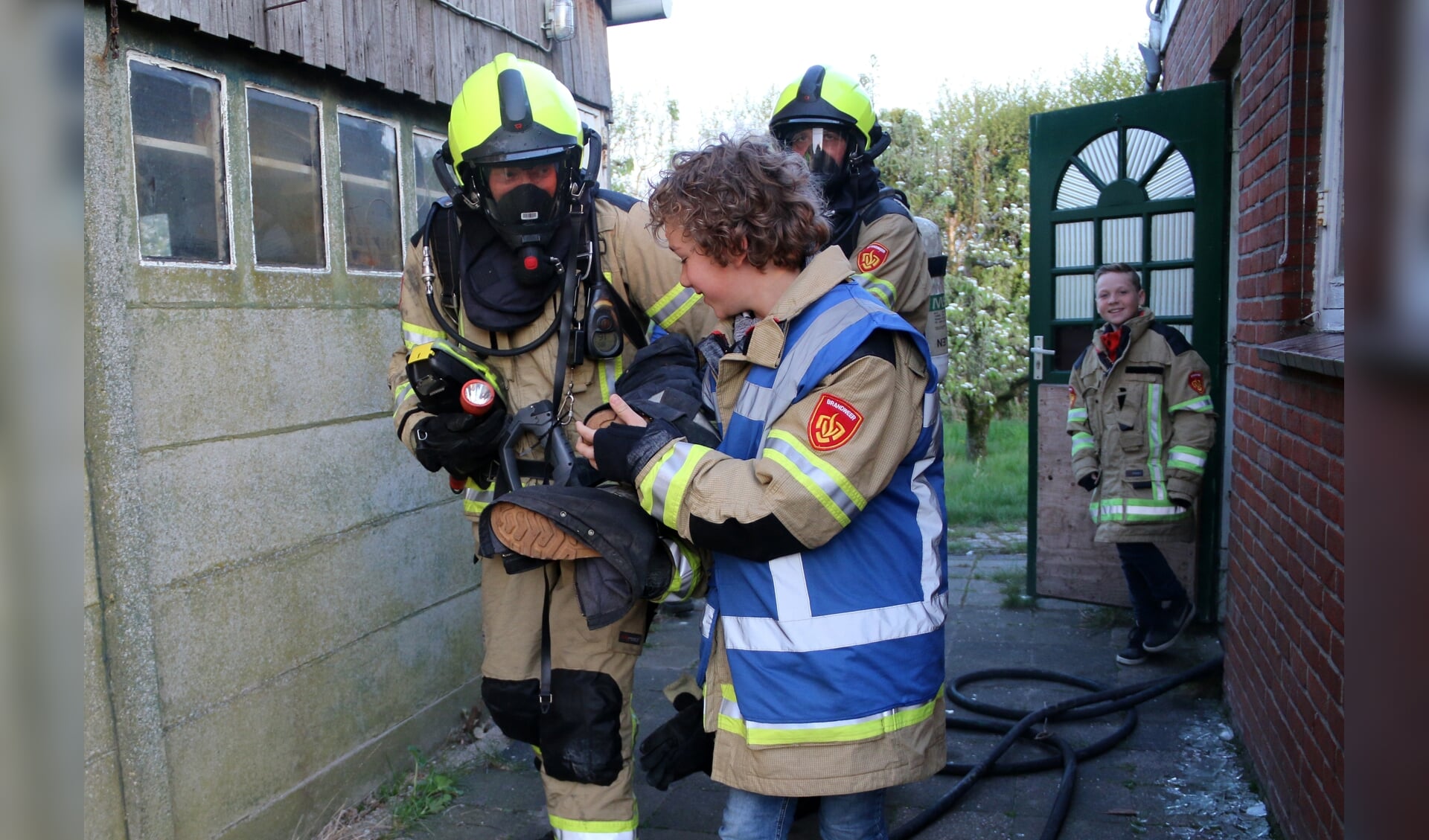 Kinderburgemeester Hessel helpt brandweerlieden een 'slachtoffer' in veiligheid te brengen.