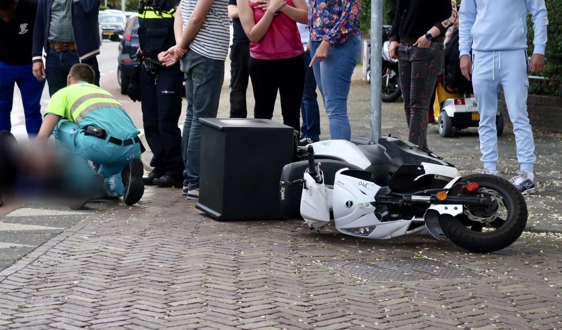 De scooter viel door de botsing op de grond. 