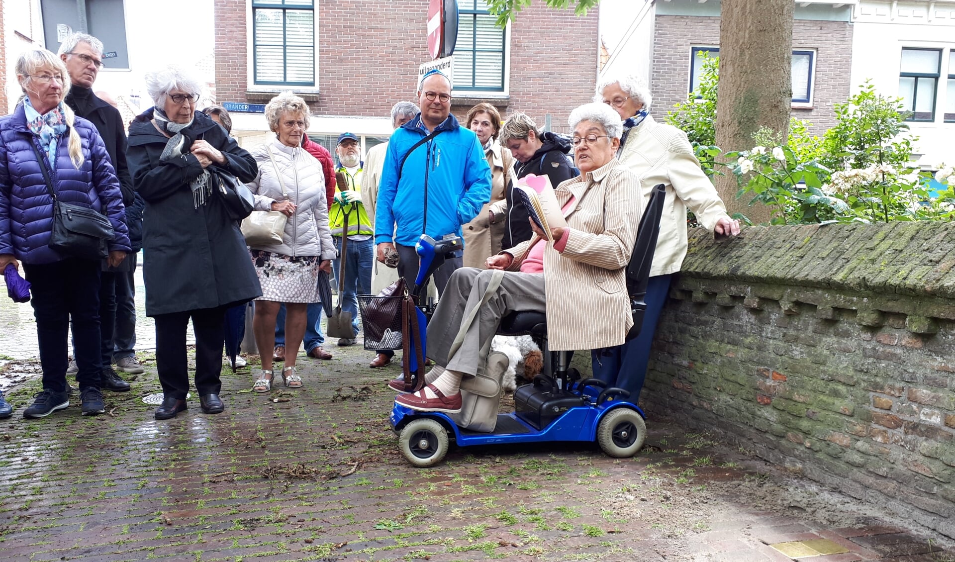 Chawwa Wijnberg draagt een gedicht voor bij de struikelstenen, rechts op de voorgrond.