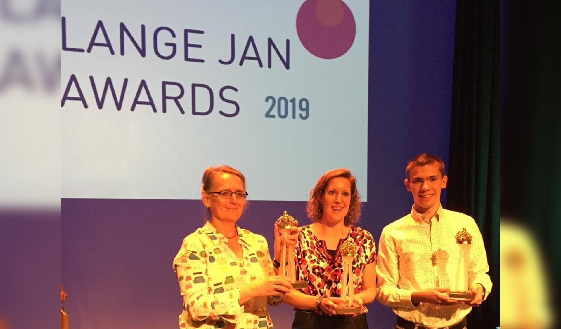 Een vertegenwoordiger van de Luisterlijn, Michelle Baas en Anderd van den Bosse met de Lange Jan Award.
