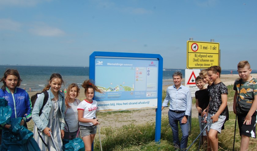 Britt (links naast bord) en enkele van de andere opruimers, zoals burgemeester Hieltjes (rechts naast bord).