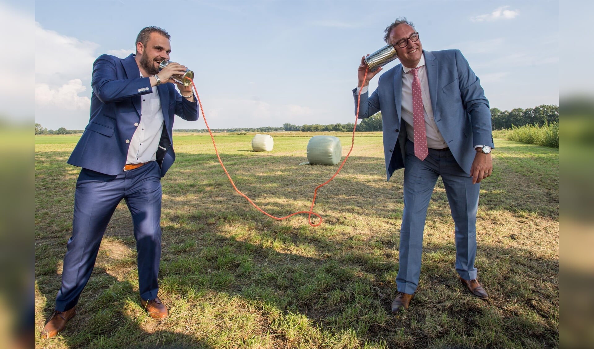 De voor de foto nog even 'ouderwets' communicerende wethouders Martin van der Bijl (links) en Patrick Kok. Snel internet via een glasvezelnetwerk moet straks een belangrijke bijdrage leveren aan de digitale toegankelijkheid van de gemeenten, en dan met name het buitengebied. 