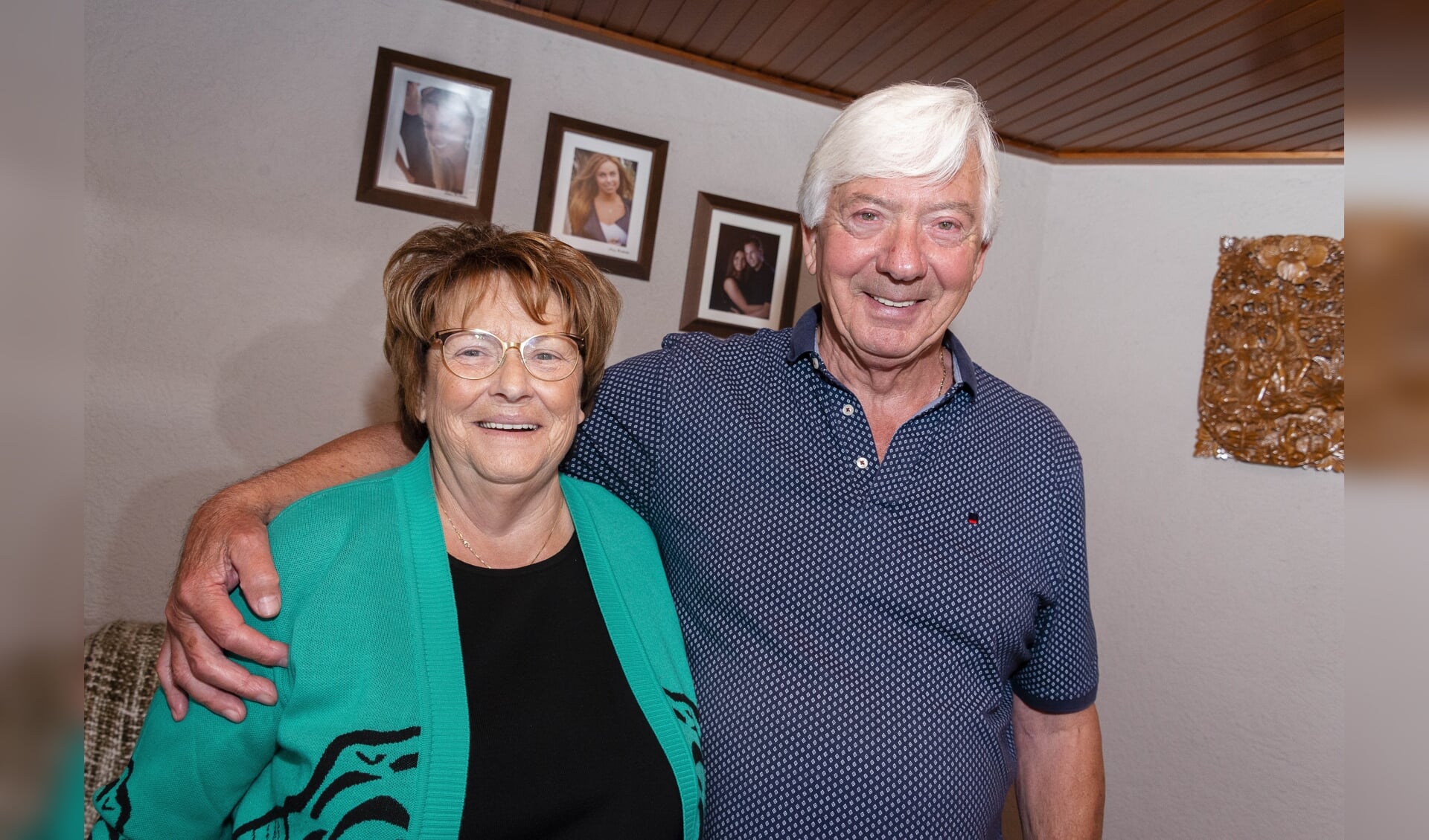 Het jubilerende echtpaar poseert bij de foto's van de kleinkinderen. 