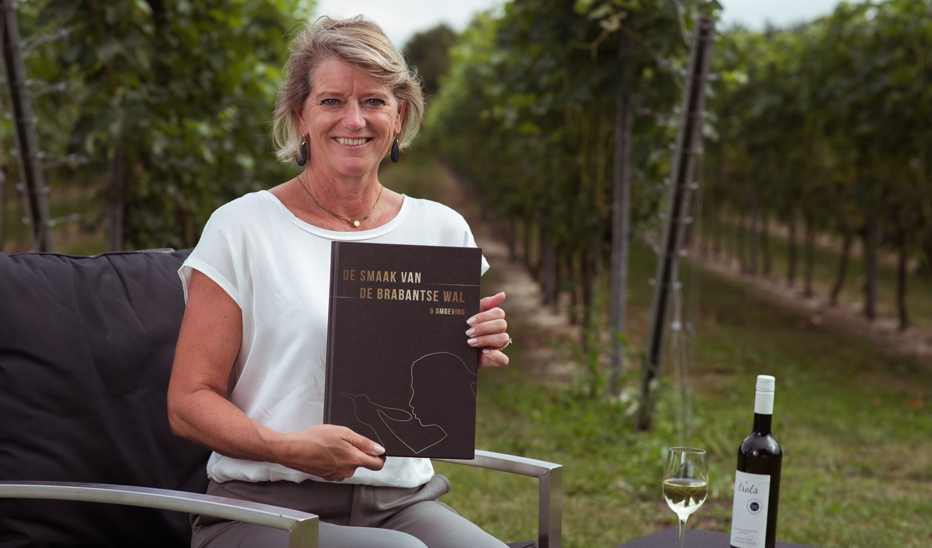 Margot Haest met haar boek in de wijngaard van Domaine De Brabantse Wal FOTO GIJS PROOST FOTOGRAFIE