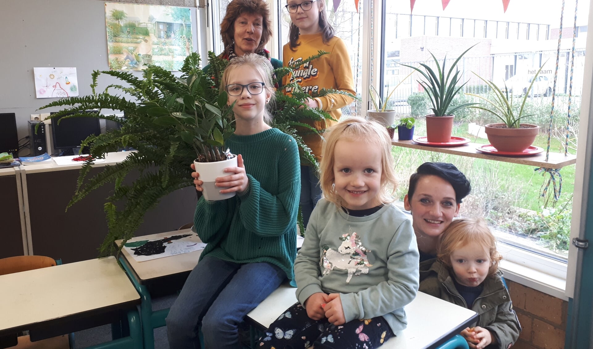 Groene juf Marjan, Babette, Nova Joan, Elodie, groene moeder Digna en zoontje Kamiel tussen de planten in de klas.
