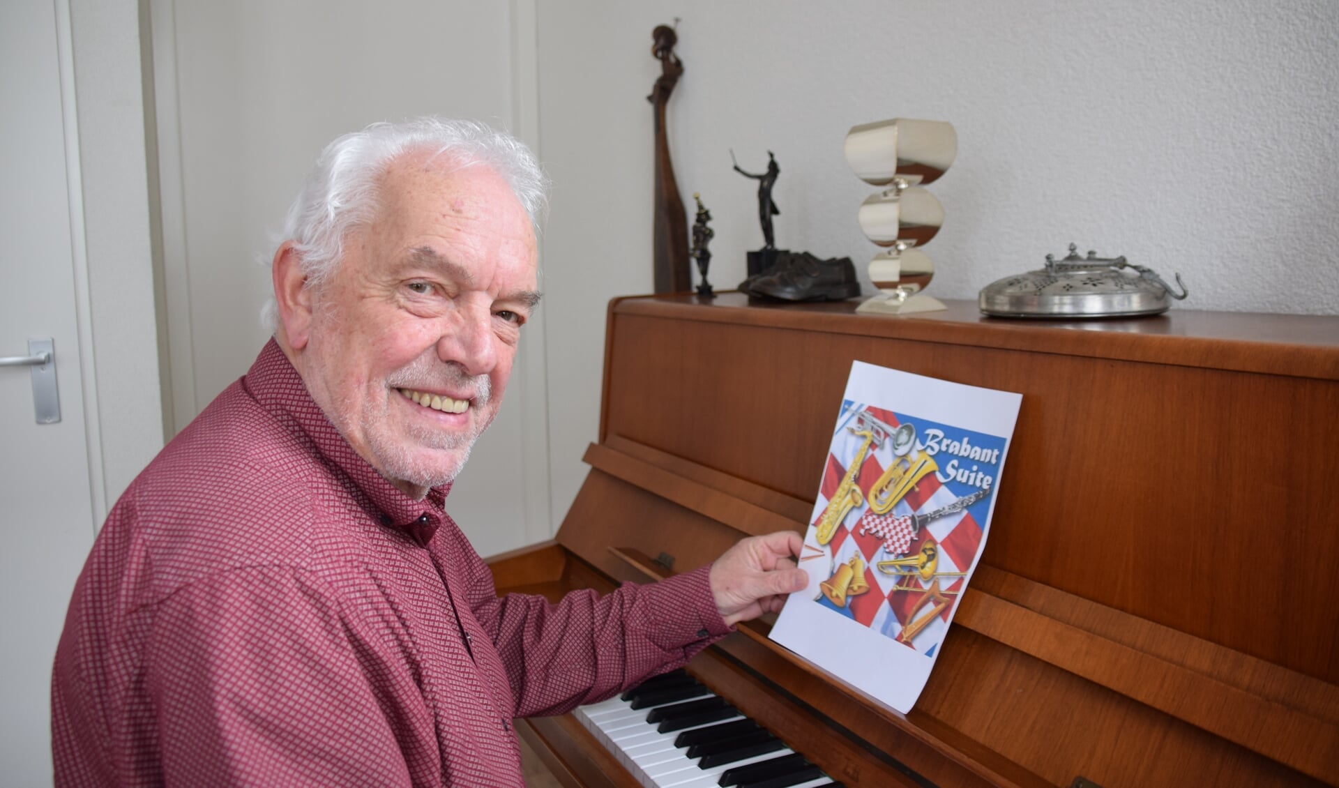 Theo Wouters met de CD hoes en op de piano zijn zilveren 'hoeders' bokaal. FOTO STELLA MARIJNISSEN