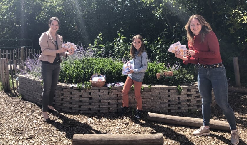 Joyce Verwijs van boekhandel Dieleman (l) reikt op het Natuurplein de boekenbonnen uit aan Kaya Dekkers en juf Carmen Bastiaanse.