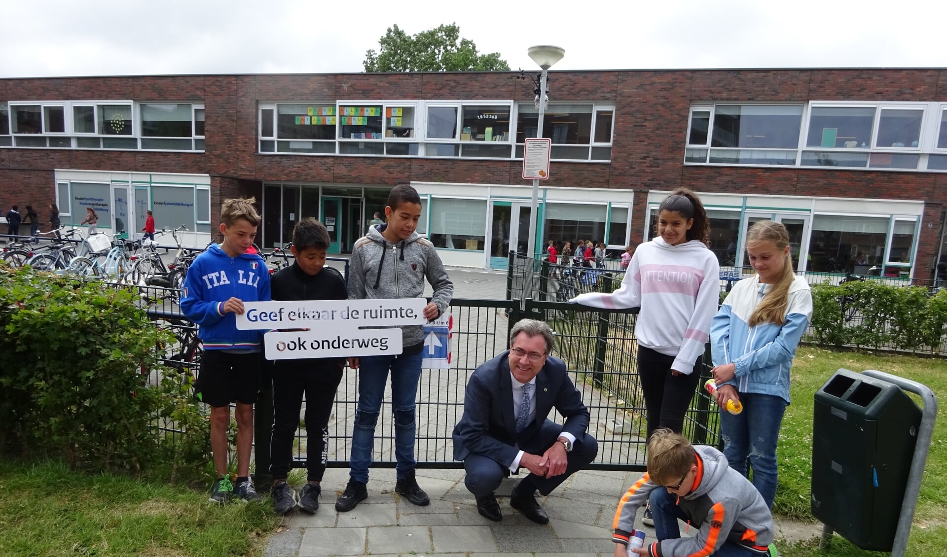 Kinderen van de Cypressenhof en gedeputeerde Harry van der Maas spuiten de boodschap op het schoolplein. 