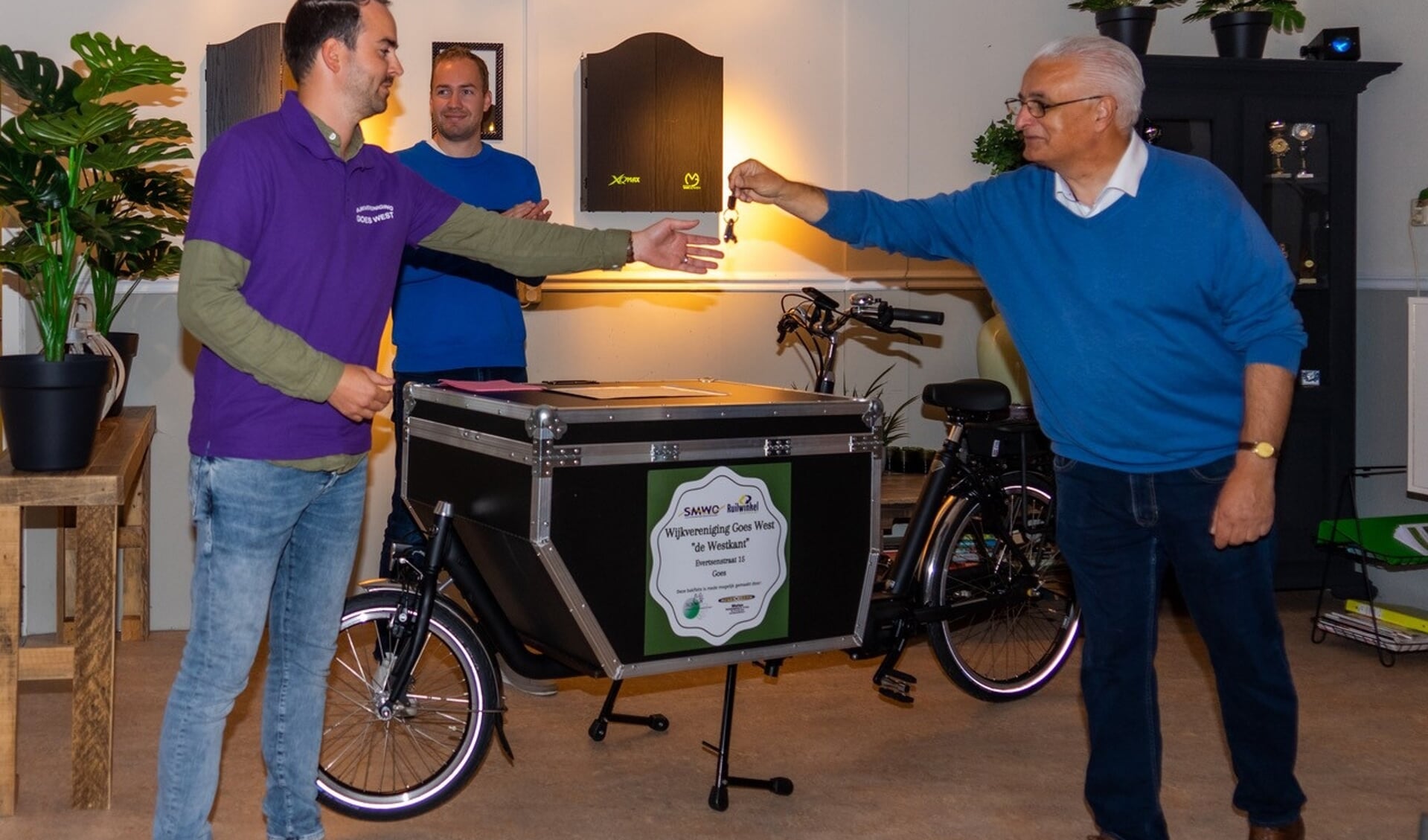Yannick de Potter, van de wijkvereniging, ontvangt de fietssleutel van Rien Heijboer van SOMV. Op de achtergrond Joost de Goffau de wijkwethouder. 