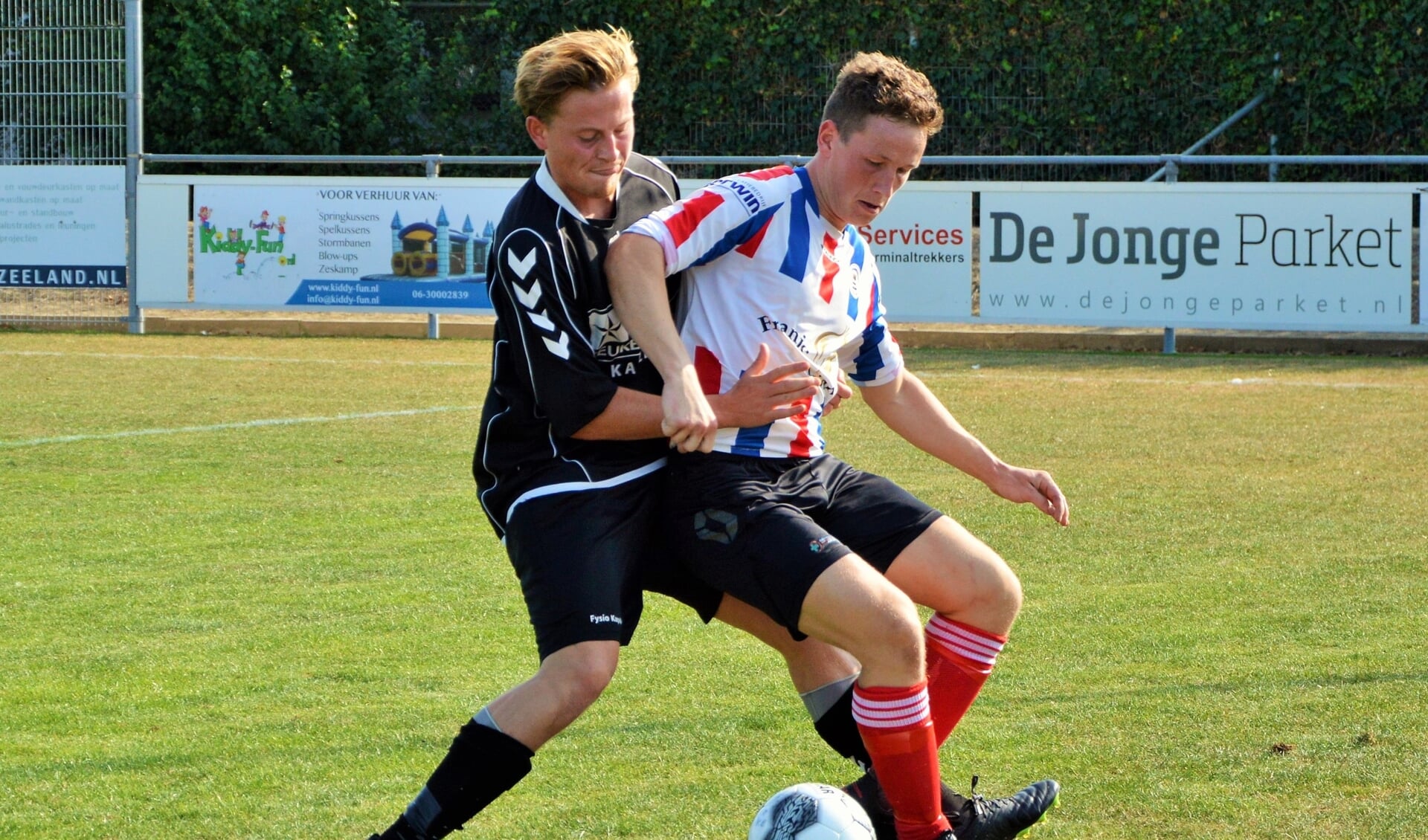 Bastiaan van Dijk (Krabbendijke) in duel met Ries de Jonge (Kapelle) in de gemeente-derby. 