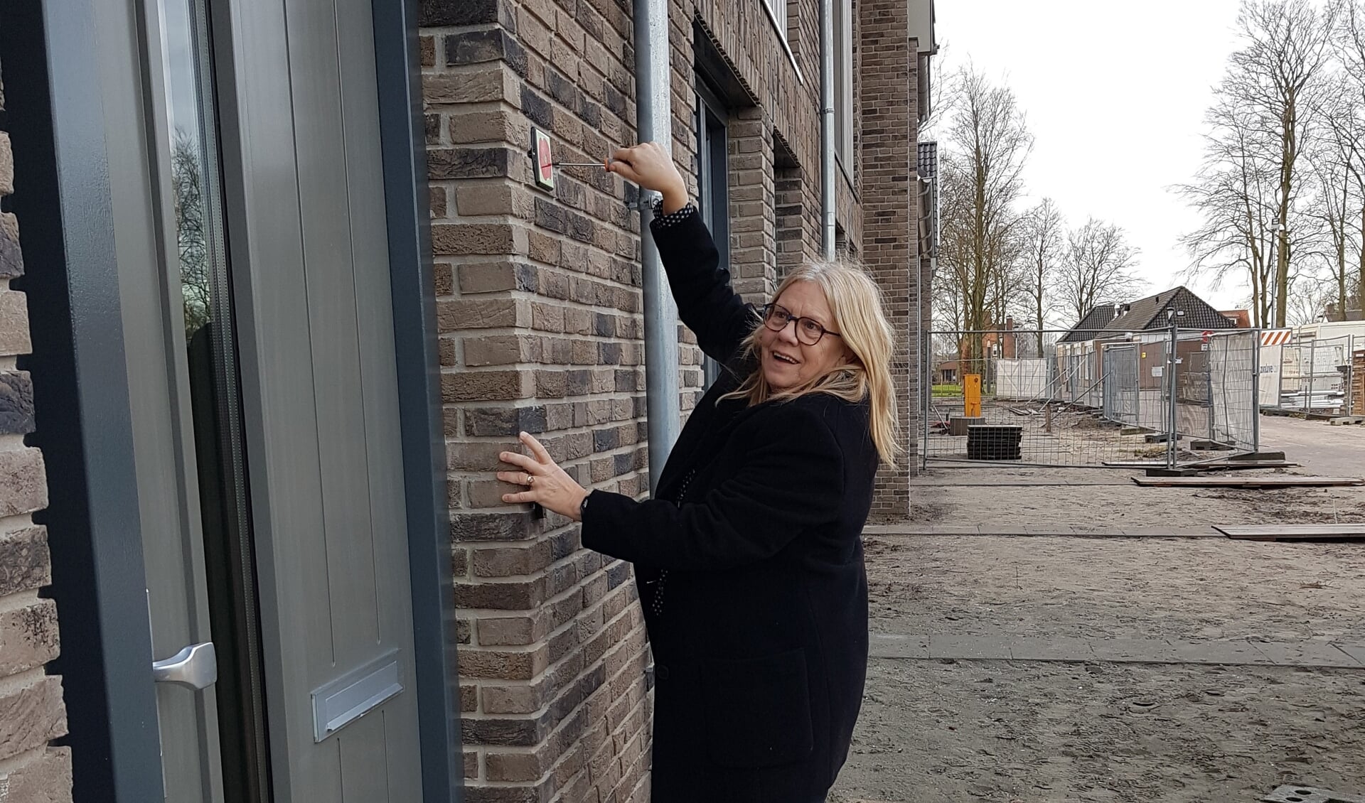 Wethouder Wilma Baartmans bevestigt een klaproosschildje aan het eerste huis aan de Piet Snoeijersstraat.