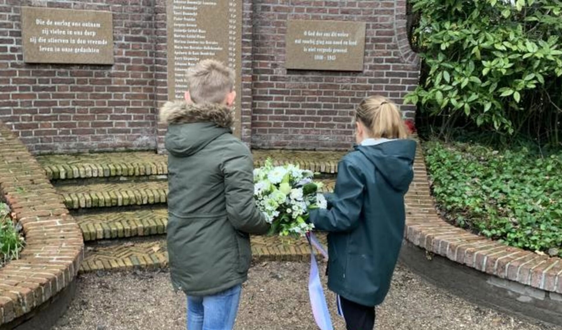 Leerlingen van Archipelschool de Golfslag Domburg leggen bloemen neer tijdens de herdenking op de Oude begraafplaats in Domburg