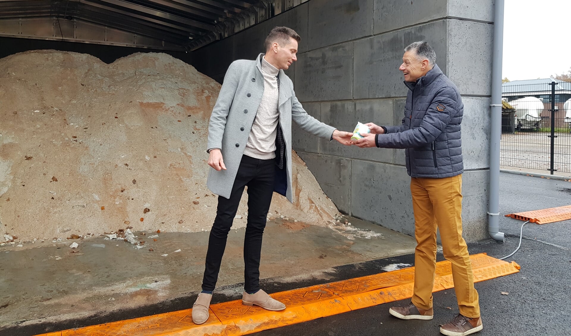 Wethouder Jeffrey van Agtmaal een pak zout overhandigt een pak zout aan teammanager Frans Linders.