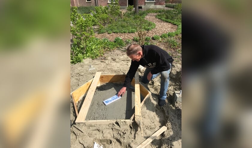 <p>Voorzitter Ad Schenk plaatst het blik in de fundering.</p>