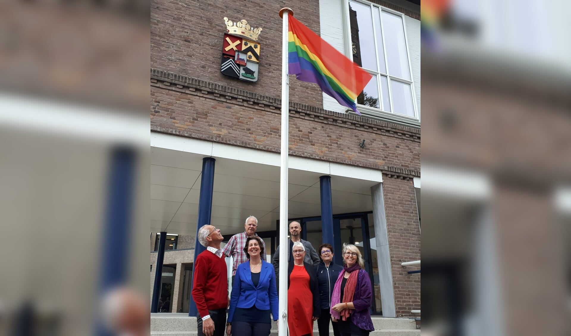 Annebeth Evertz (linksvooraan met blauwe blazer) in 2018 bij het hijsen van de regenboogvlag bij het Kapelse gemeentehuis.