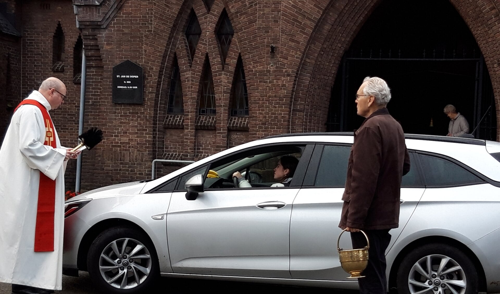 Pastoor Maickel Prasing zegent de auto van een belangstellende automobilist
