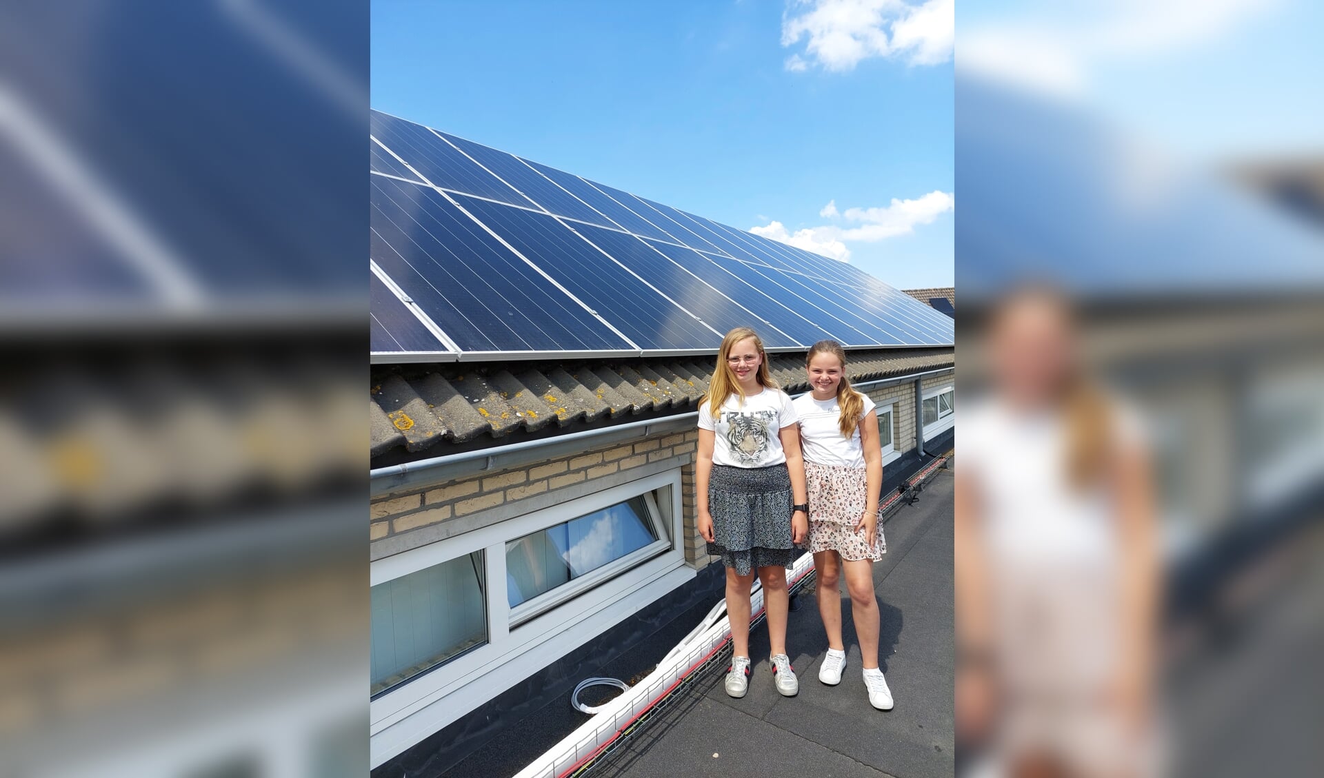 Corlinde (l) en Annelize laten op het dak van hun school de zonnepanelen zien.