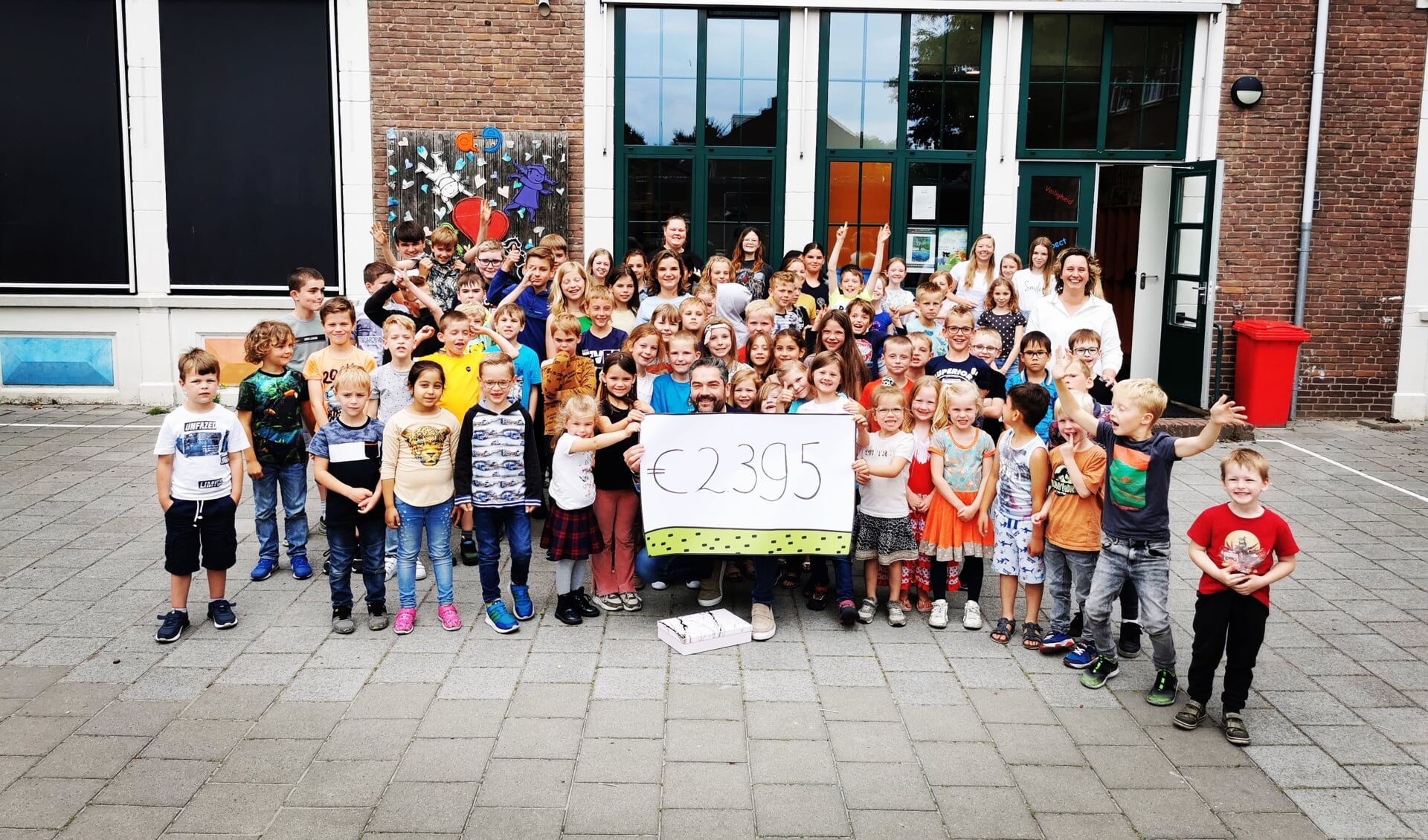 Marc Ketelaar samen met de kinderen van basisschool De Steiger en het overhandigde bedrag.