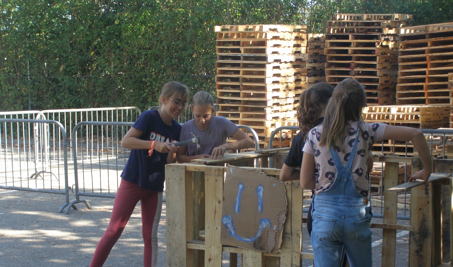 Kinderen bouwen een dorp met hout van pallets.