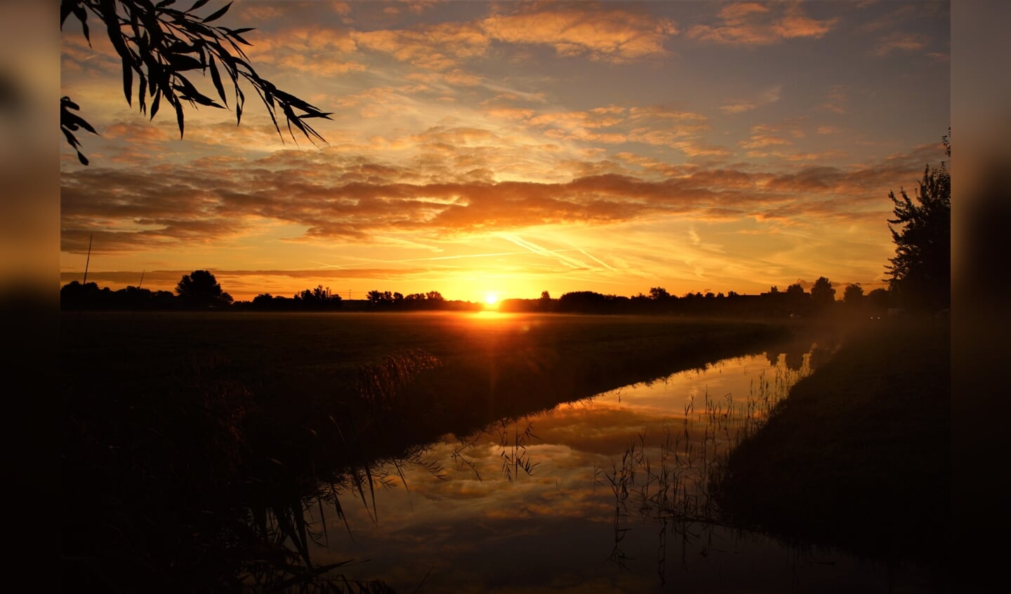 Zonsopkomst met morgenrood en grondmist en weerspiegeling.