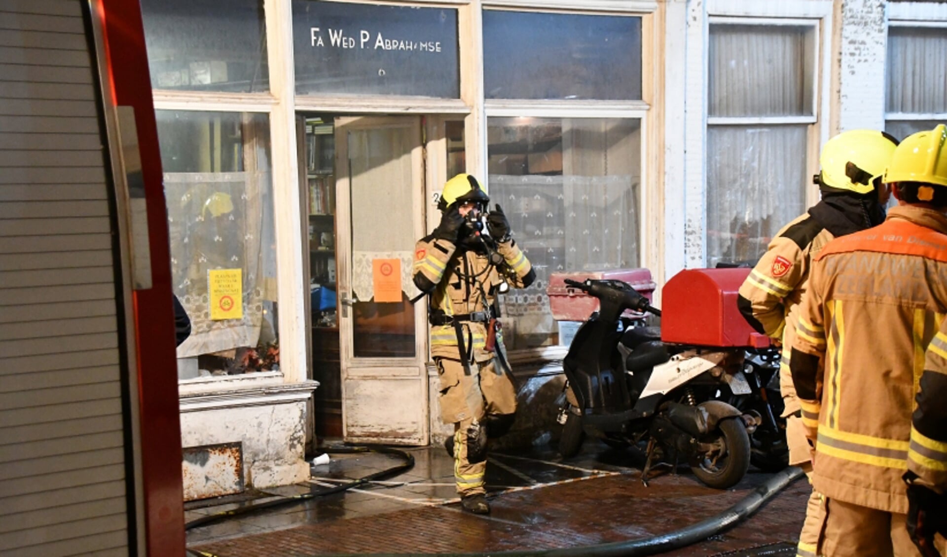 Een brandweerman verlaat het pand van de voormalige Fa. Wed. Abrahamse aan de Vlasmarkt